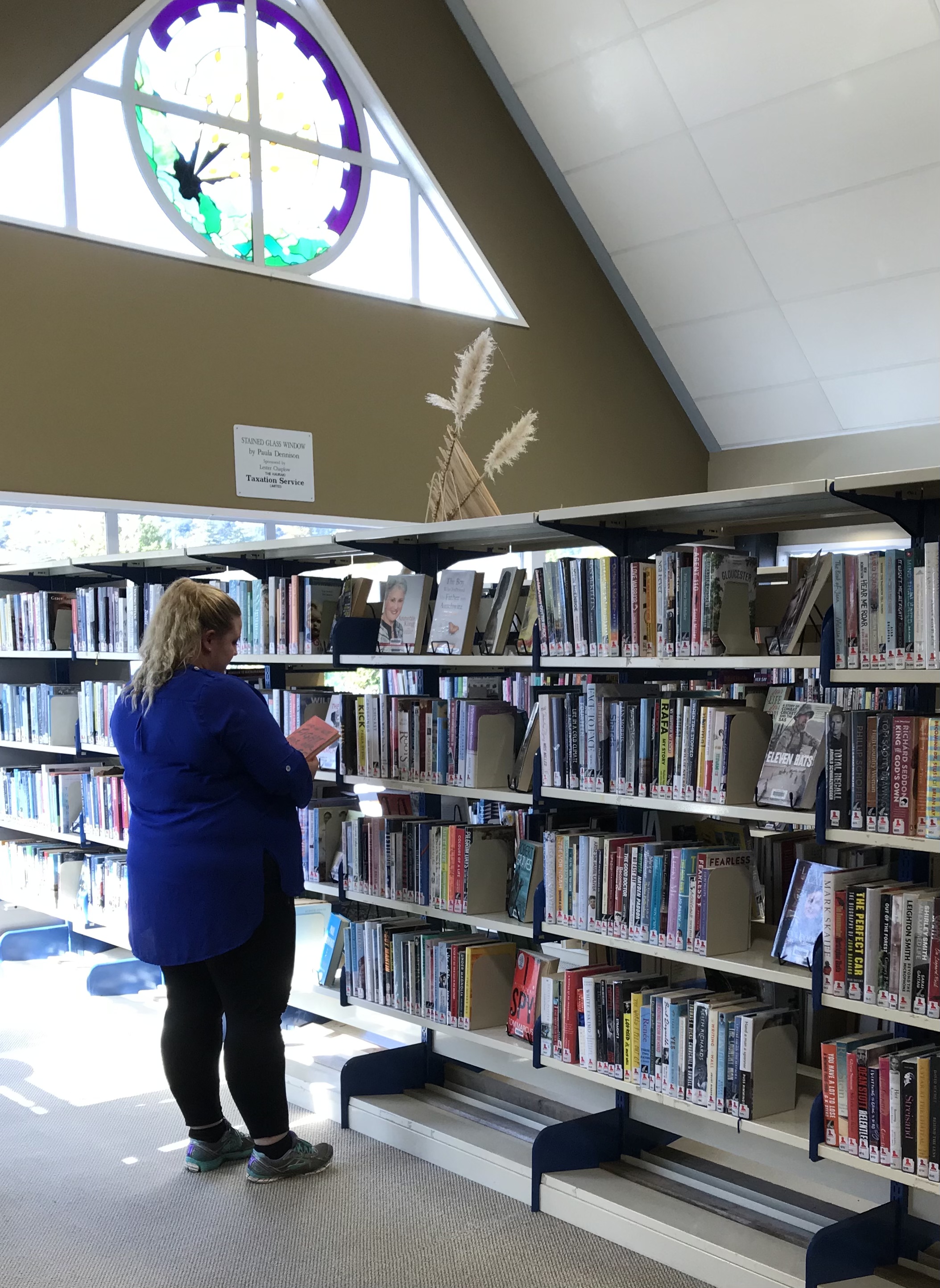 Browsing Thames Library shelves with stained glass window in the background